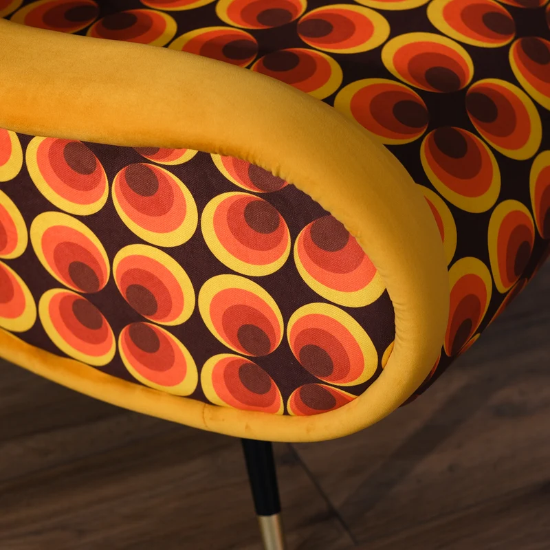 Poltrona Miss motivo vintage arancio, senape e marrone, gambe nere dettaglio ottone