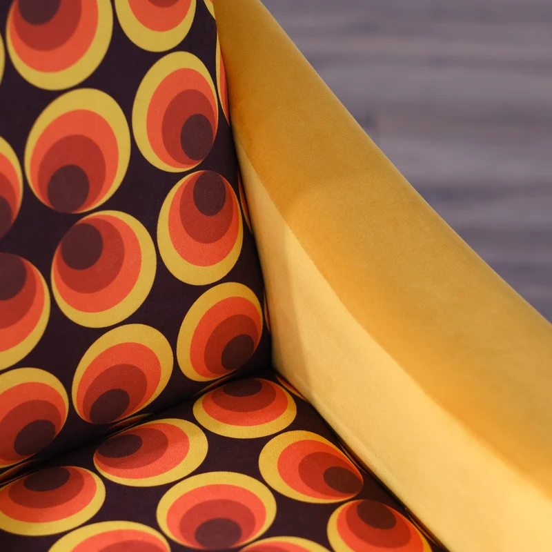 Poltrona Miss motivo vintage arancio, senape e marrone, gambe nere dettaglio ottone
